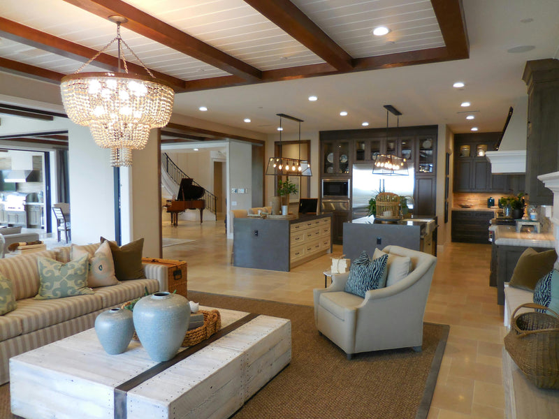 Modern living room with a chandelier, sofa, coffee table, and kitchen in the background.