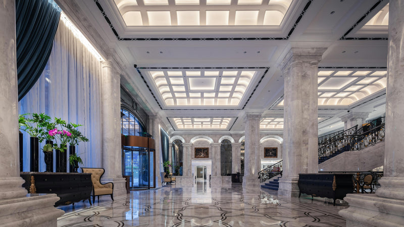 Luxurious hotel lobby with marble floors, high ceilings, and elegant decor.