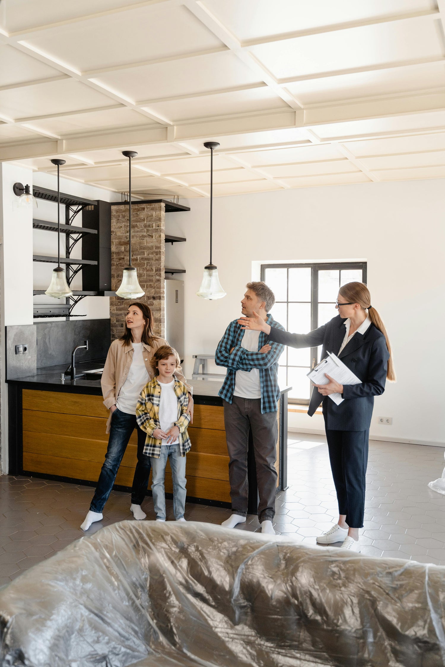 Real estate agent showing a home to a family, with a covered couch in the foreground.