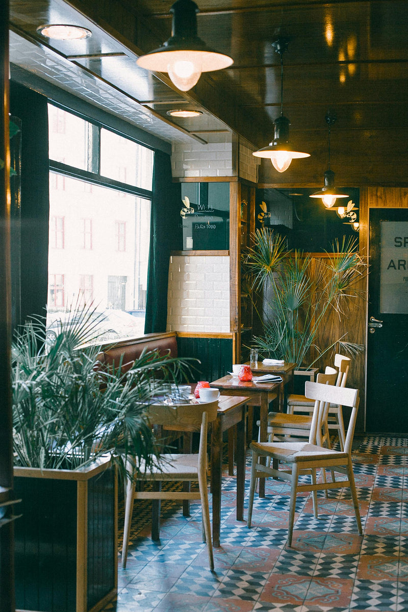Interior of a cafe with tables, chairs, and plants.